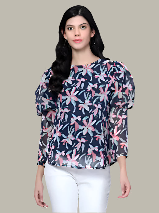 Woman wearing a navy blue floral blouse with white pants on a beige background